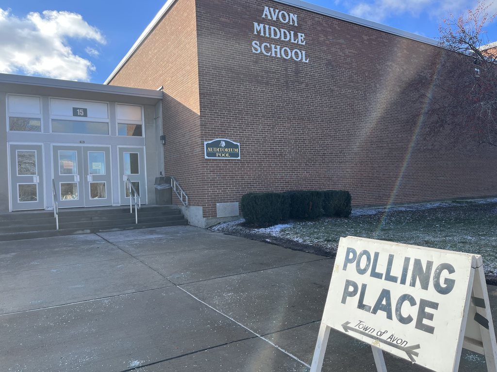 The exterior of the Avon Middle School Auditorium entrance with a 'Polling Place' sign out front.