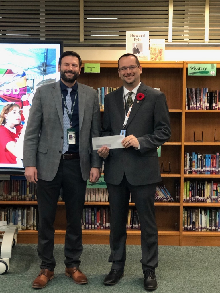 High School Principal Ryan Wagner presents Livingston County Veteran Services Director David Terry with a check for the proceeds from the district's Veterans Day 5K run/walk in November. 