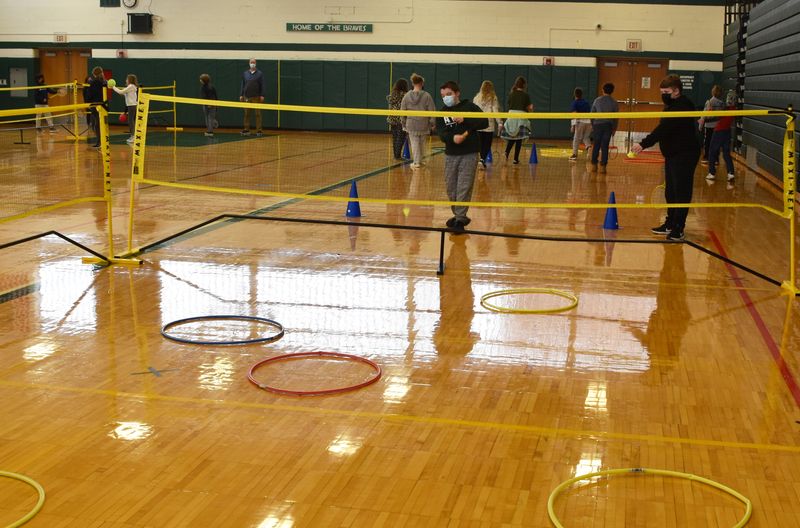 Students practice serving over the net.